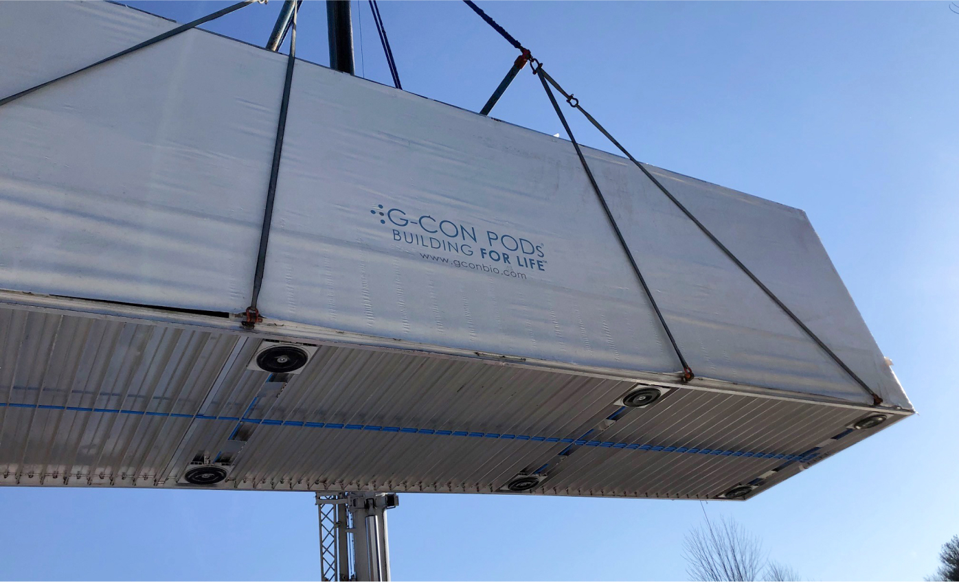 A POD being lifted into the air by a crane outdoors.